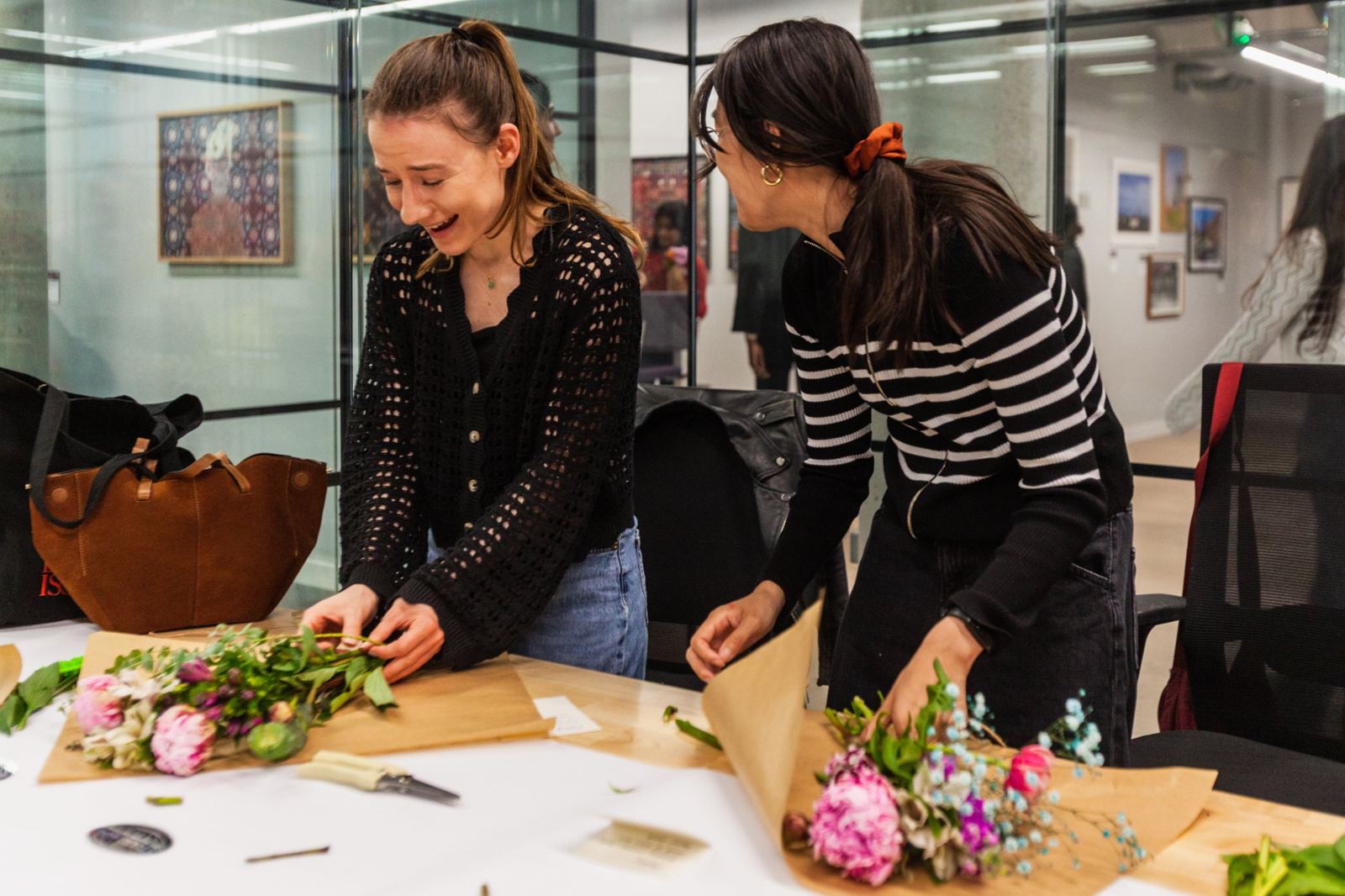 Two people laughing while wrapping their bouquets